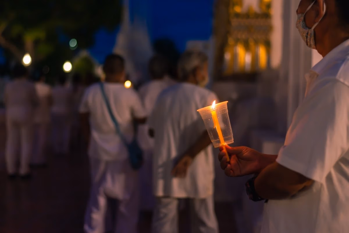 Buddhist devotees holding candles during a candlelight ceremony at a temple in Thailand